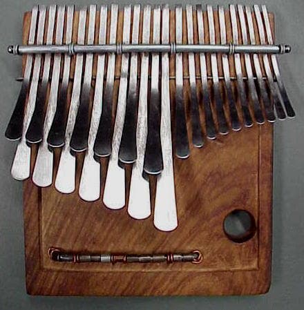 A wooden likembe thumb piano with metal tines held in a pair of hands