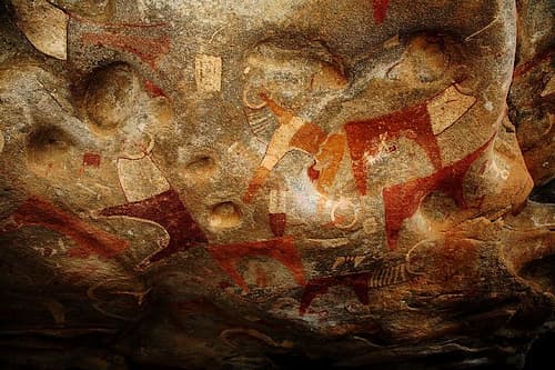 Brightly coloured ancient rock paintings of cattle and people inside a cave at Laas Geel
