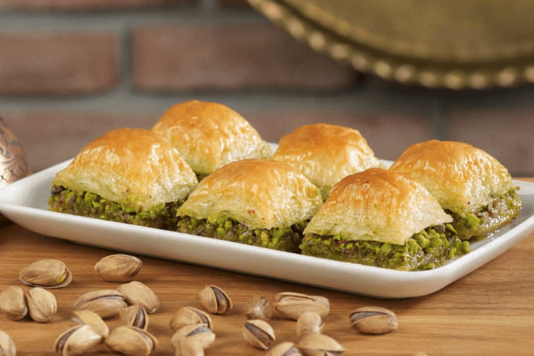 A tray of golden diamond-shaped Azerbaijani pakhlava sweets with nuts on top
