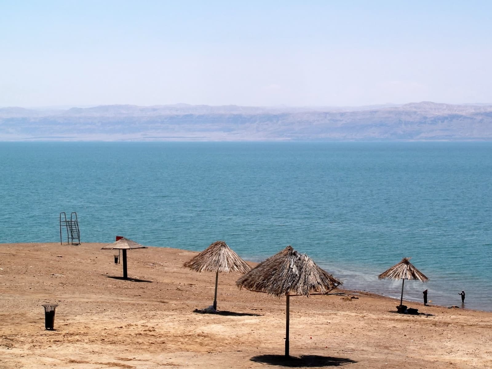 Salty white shoreline of the Dead Sea with calm blue water