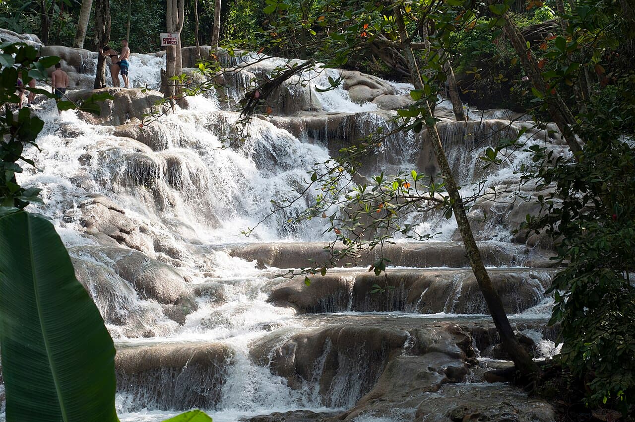 Visitors climbing the stepped terraces of Dunn's River Falls in the sunshine