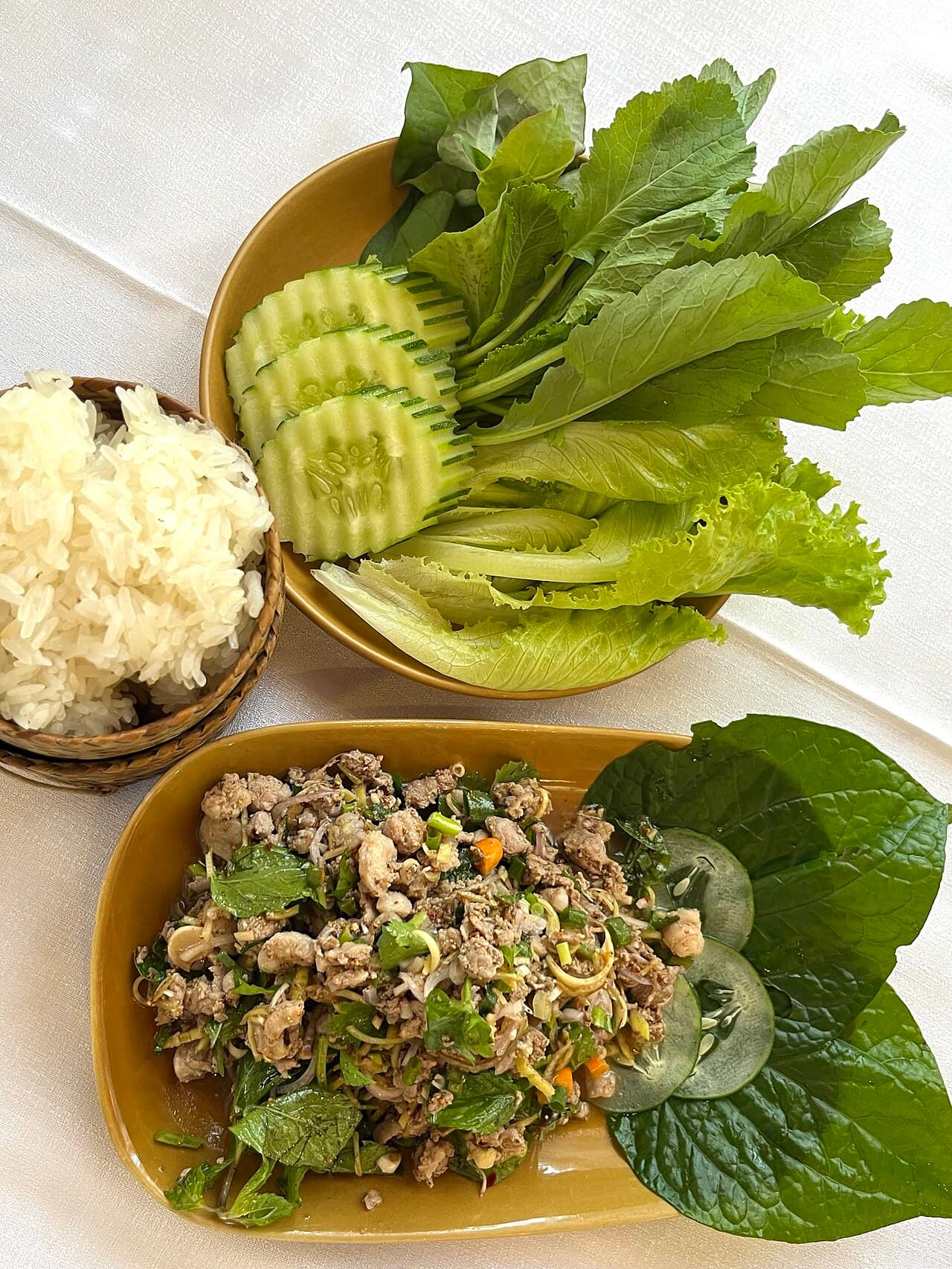 A bowl of fresh vegetable laap with herbs, chopped vegetables and toasted rice flakes