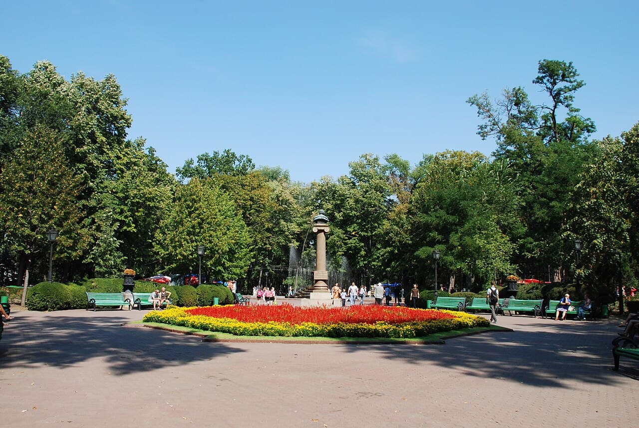 A wide tree-lined boulevard in central Chișinău with flower beds and benches