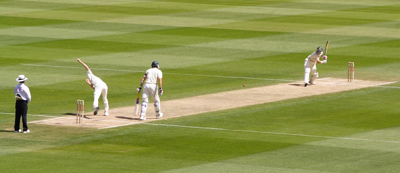A cricket match being played on a ground in Saint Vincent with green hills in the background