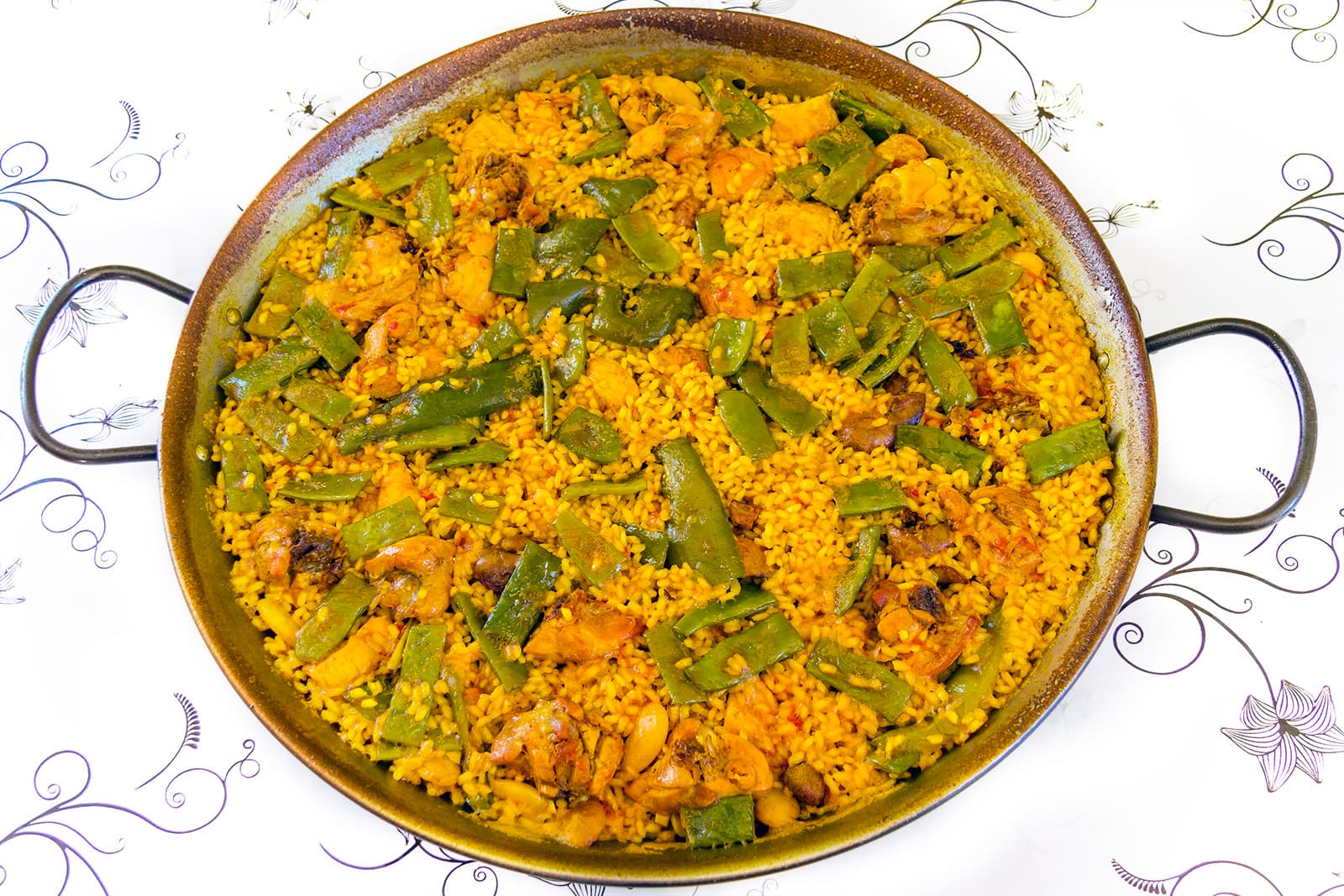 A pan of paella valenciana with rice, chicken, green beans and saffron